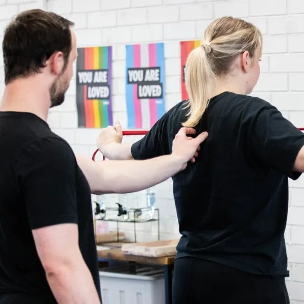 Woman stretching resistance band with trainer assistance